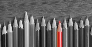 black and white photo of pencils lined up on a special education teacher's desk, with one pencil colored in red.