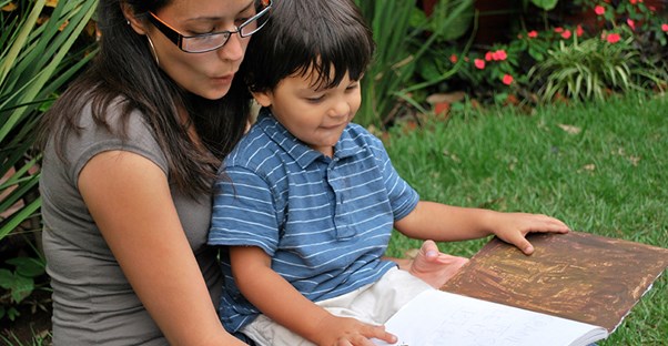 special education teacher with a masters degree reading a book to a child on her lap