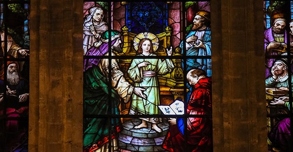painted glass windows of a church with a pastor who has a theology degree