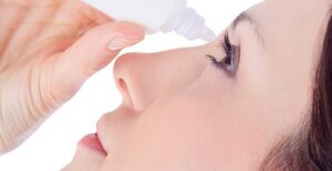 girl treating her itchy eyes with eye drops