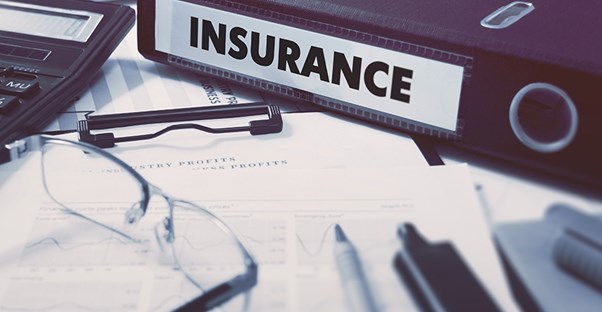 a business desk with an insurance binder for the company to research whether they need liability insurance or not