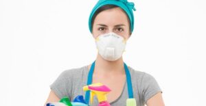 A woman holding a box of cleaning supplies is ready to deep clean her home.