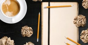 A copywriter brainstorms over a blank notebook and a cup of coffee