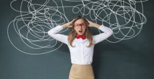 woman standing in front of a chalk board with chaos to represent what it is like to have aphasia