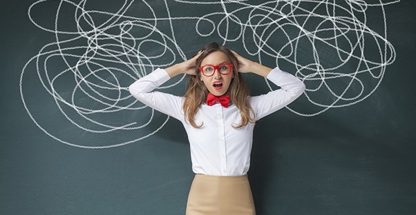 woman standing in front of a chalk board with chaos to represent what it is like to have aphasia