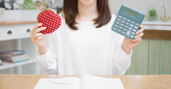 Lady comparing calculator and purse wallet. Cost of Living.