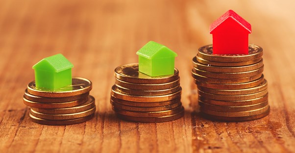 Coin and toy house stacks, increasing in size. Mortgage.