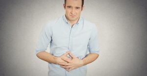 Man holding stomach in pain. Pancreatitis causes.