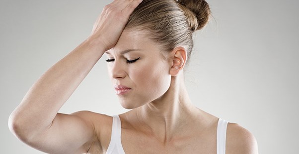 Woman holding her head in pain. Traumatic brain injury.