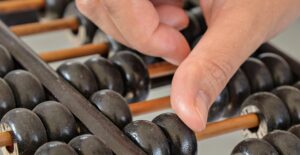 Hand counting rings on an abacus. Actuary salary.