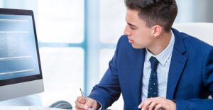 Man checking computer at desk. Actuary vs writer.