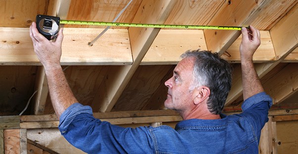 Man measuring ceiling beams. Home inspection.