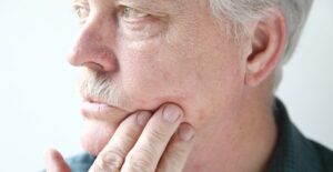 a man feels the psoriasis on the side of his face