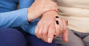 A caregiver holds the hand of an elder patient.