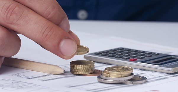 a person calculates home investment with calculator and coins