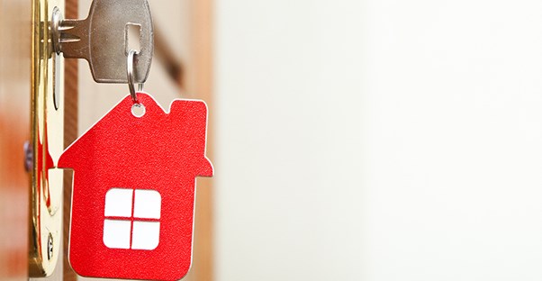a key with a house keychain inserted into a door lock