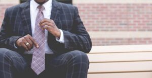 a small business owner adjusts his tie and ponders his retirement plan options