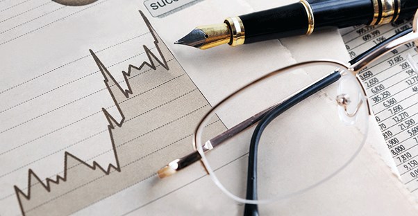 a paper report of index funds and etfs with a pen and glasses lying on top