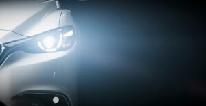 the headlight of a luxury car shines toward the camera