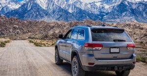 a hybrid suv makes its way down a dirt road toward mountains