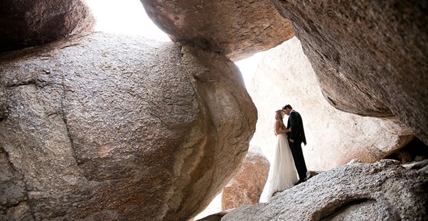 a couple stands between large boulders during an arizona wedding photoshoot