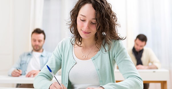 a woman and two men take practice lsat exams at a test prep center