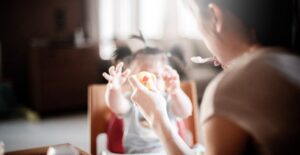 a woman feeds her young daughter solid foods