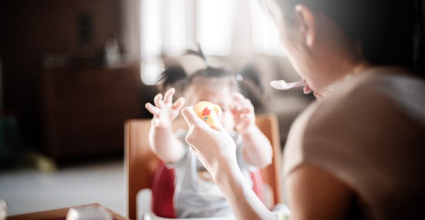 a woman feeds her young daughter solid foods