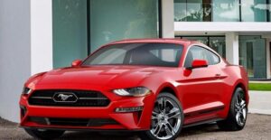 a red 218 ford mustang in a driveway