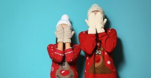 a young couple wearing ugly christmas sweaters on blue background