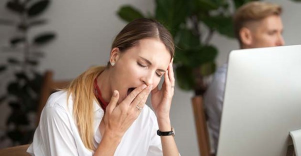 Woman covering her mouth to yawn.