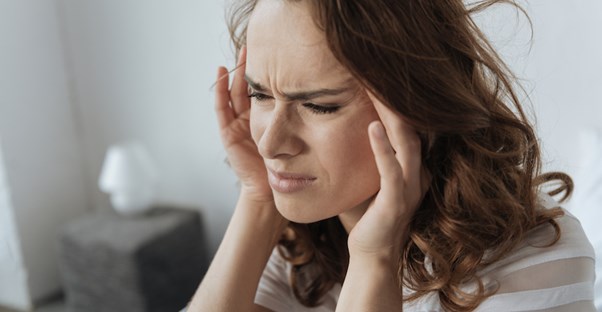 Woman with a migraine rubbing her temples.