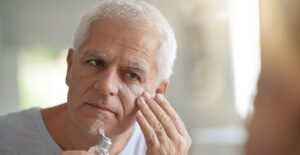 Man applying moisturizer in the mirror.