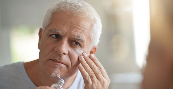 Man applying moisturizer in the mirror.