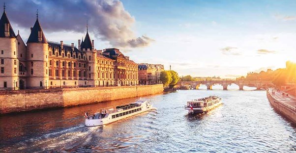 Two river boats sailing side by side with a sunset behind them