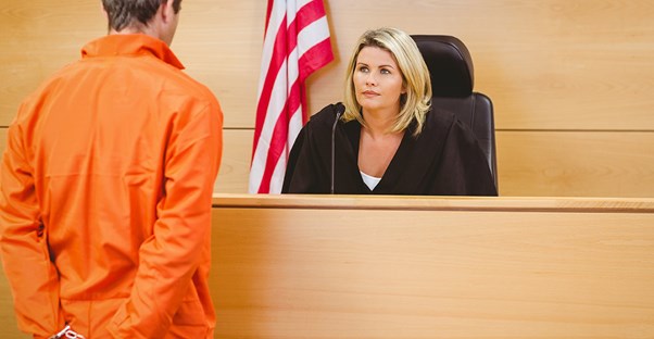 a prisoner standing in front of a judge in a court room