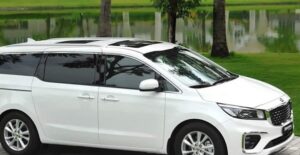 a white 2019 kia sedona parked near a pond in a nice neighborhood
