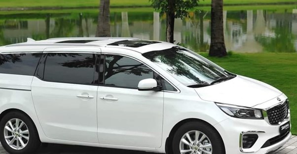 a white 2019 kia sedona parked near a pond in a nice neighborhood