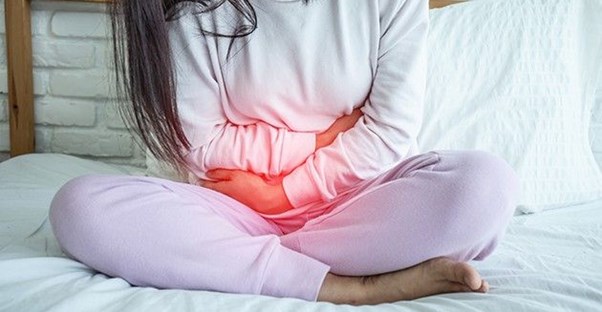 Girl sitting on bed in pain