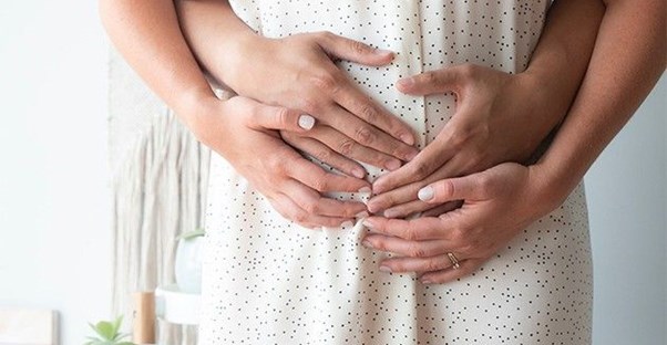 man cradles pregnant womans belly