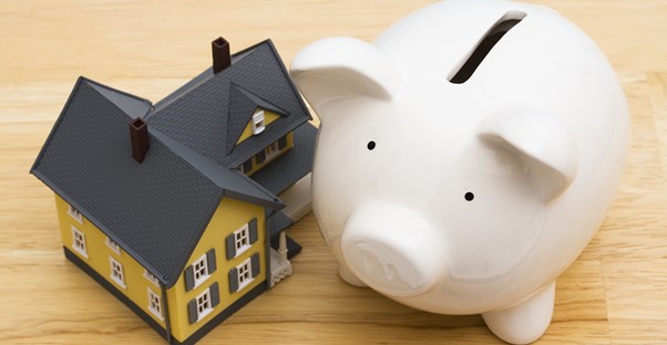Piggy bank next to a small yellow house