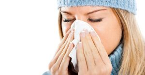 I woman blows her nose into a tissue.