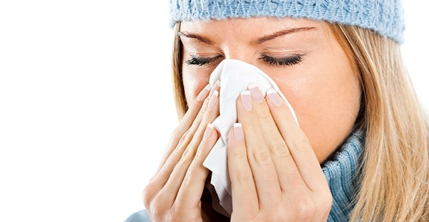 I woman blows her nose into a tissue.