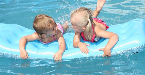 Two kids with travel insurance policies playing in a pool