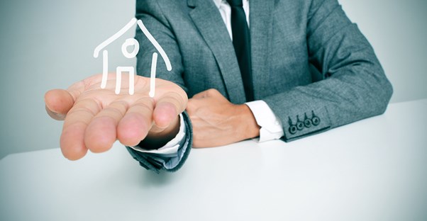 A man holds a drawn outline of a house in his hand.