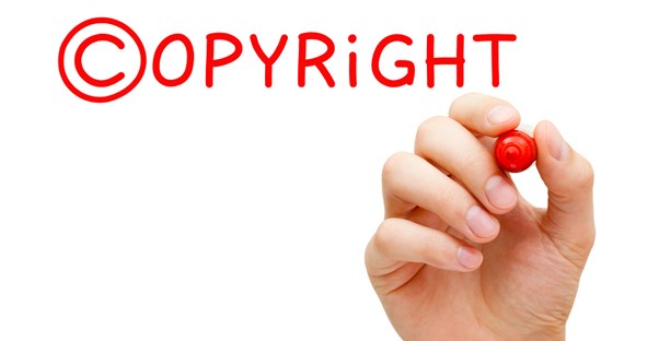 hand with a red pen writing the word copyright