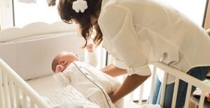 Mother picking baby up from crib