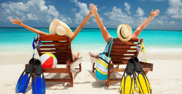 a couple sitting in chairs on the beach with their arms outstretched toward the sun