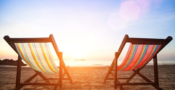 two empty beach chairs in front of an ocean sunset