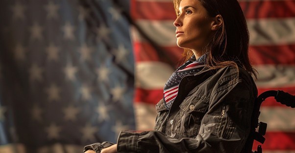A Young Disabled Veteran in a Wheelchair in Front of the American Flag